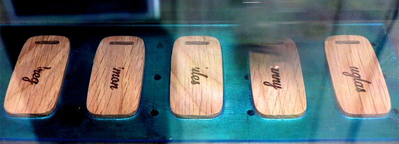 Custom wooden name badges being personalised by precision laser engraving for corporate events