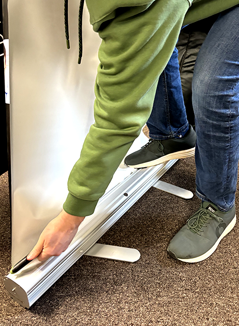 Staff recycling used roller banner demonstrating sustainable practices in promotional merchandise and eco-friendly corporate event materials